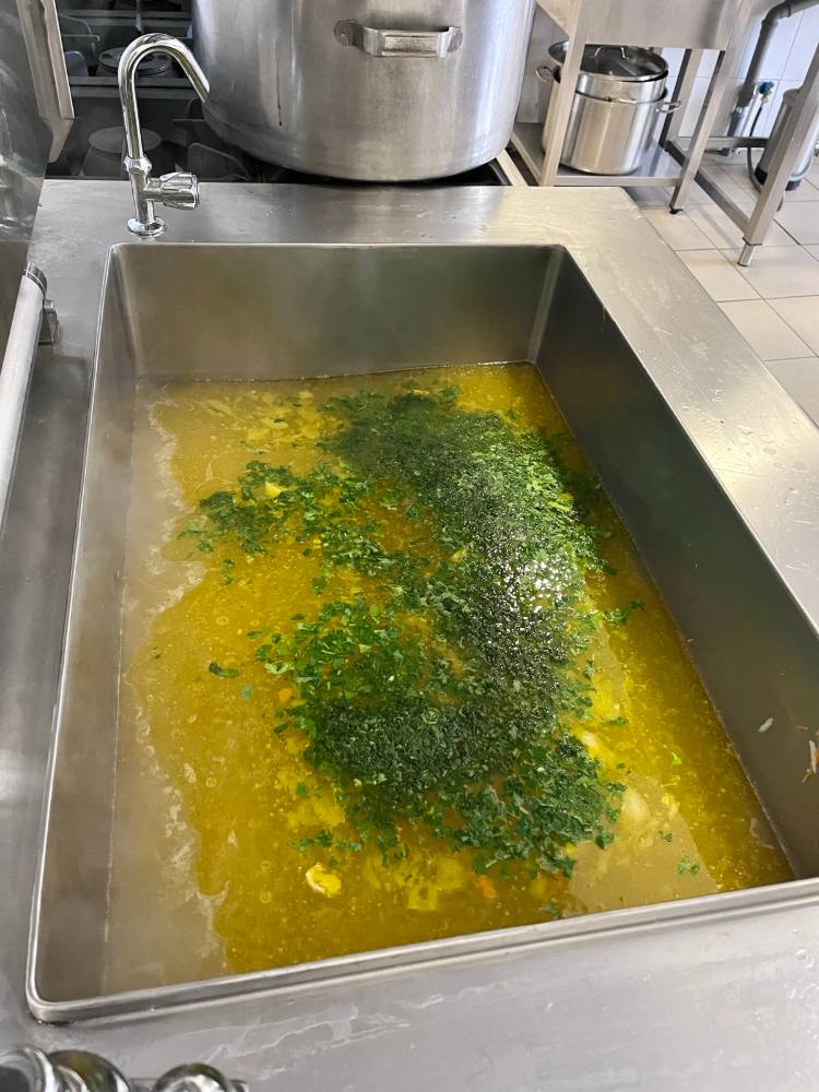 Tavă mare cu ciorbă și pătrunjel tocat, în bucătărie