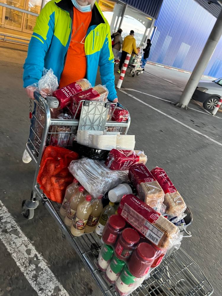 Voluntar care împinge un cărucior plin cu alimente cumpărate pentru gătit