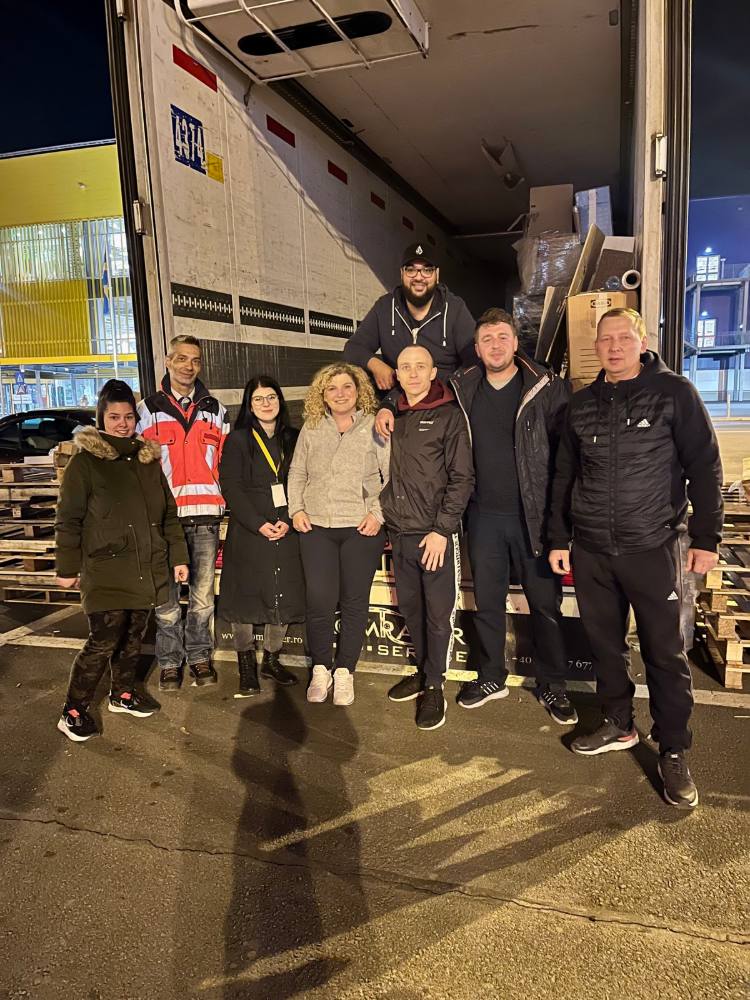 Echipa de voluntari în fața unui camion, seara