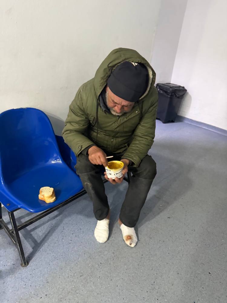 Bărbat așezat pe un scaun albastru, mâncând dintr-un castron