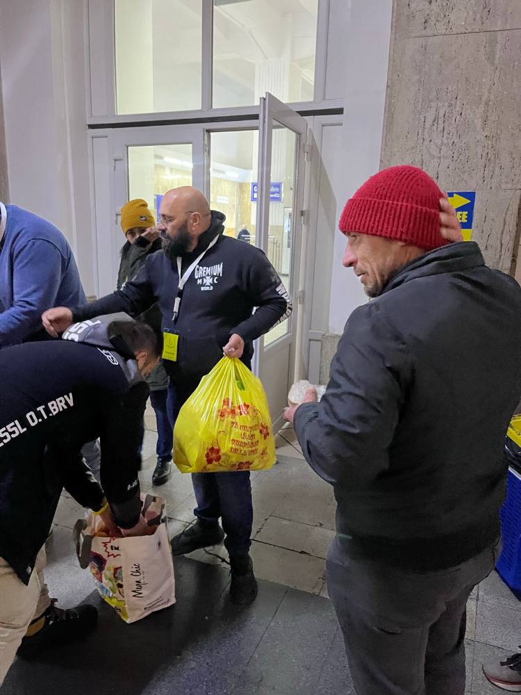 Voluntari care dau pachete cu mâncare la intrarea în gară