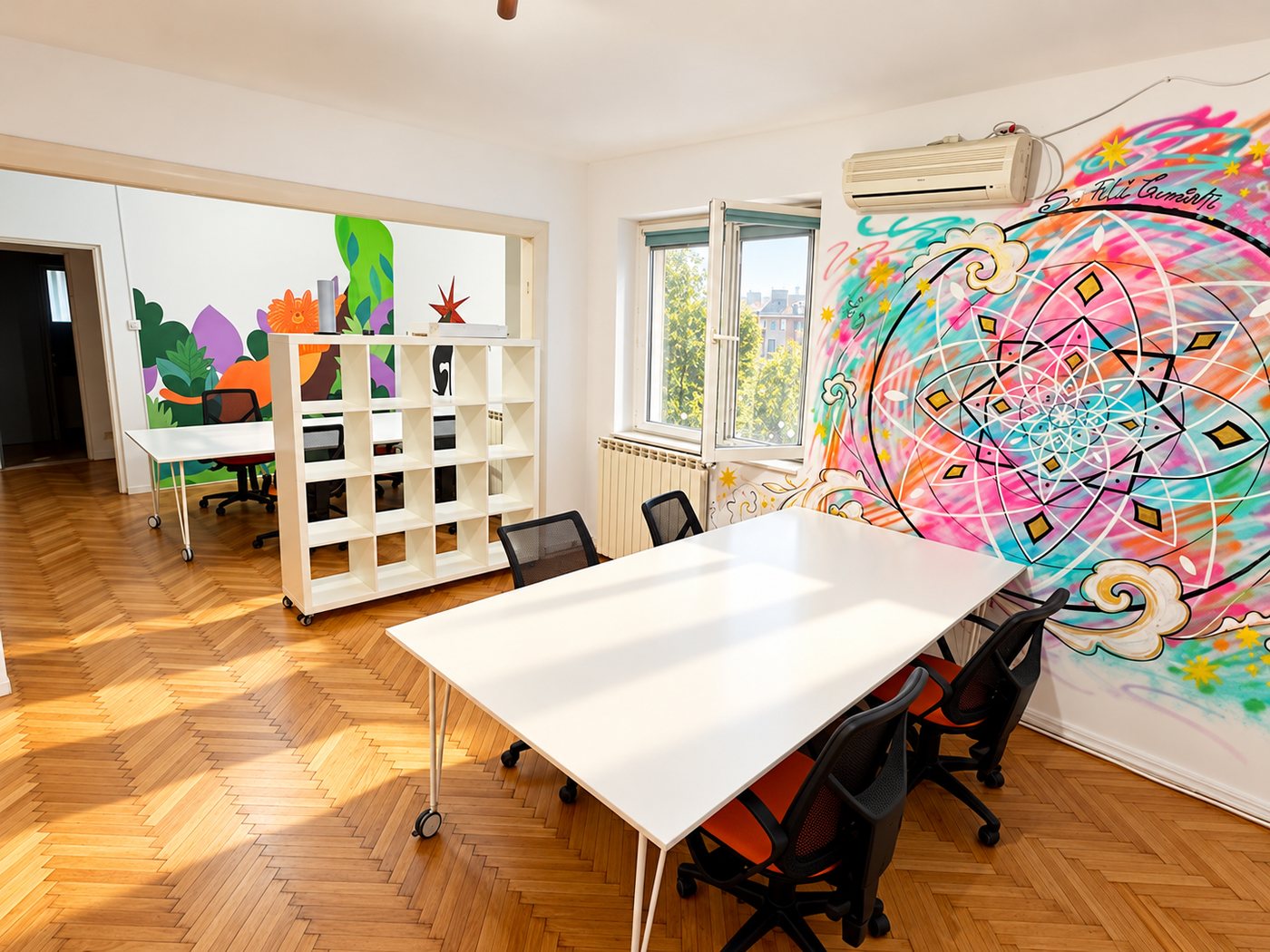 Sala principală din Helpers House, cu mese albe, parchet în spic și o pictură murală colorată cu mandala