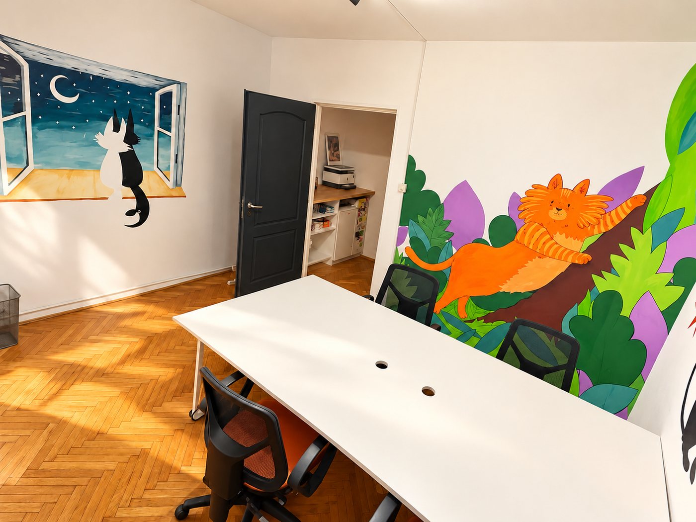 Colț de lucru cu masă albă și pictură murală cu o pisică la fereastră, sub lună, și o pisică portocalie în junglă